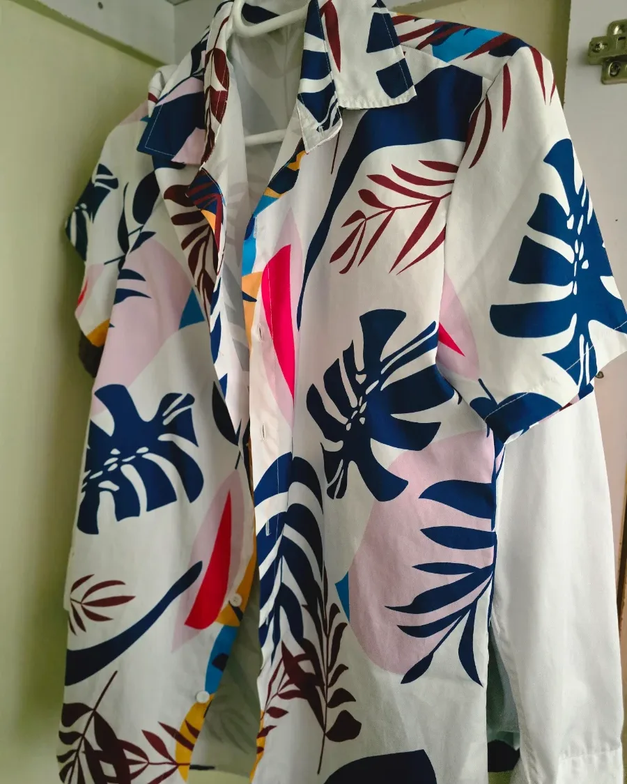A floral camp shirt on a hanger in front of a wardrobe