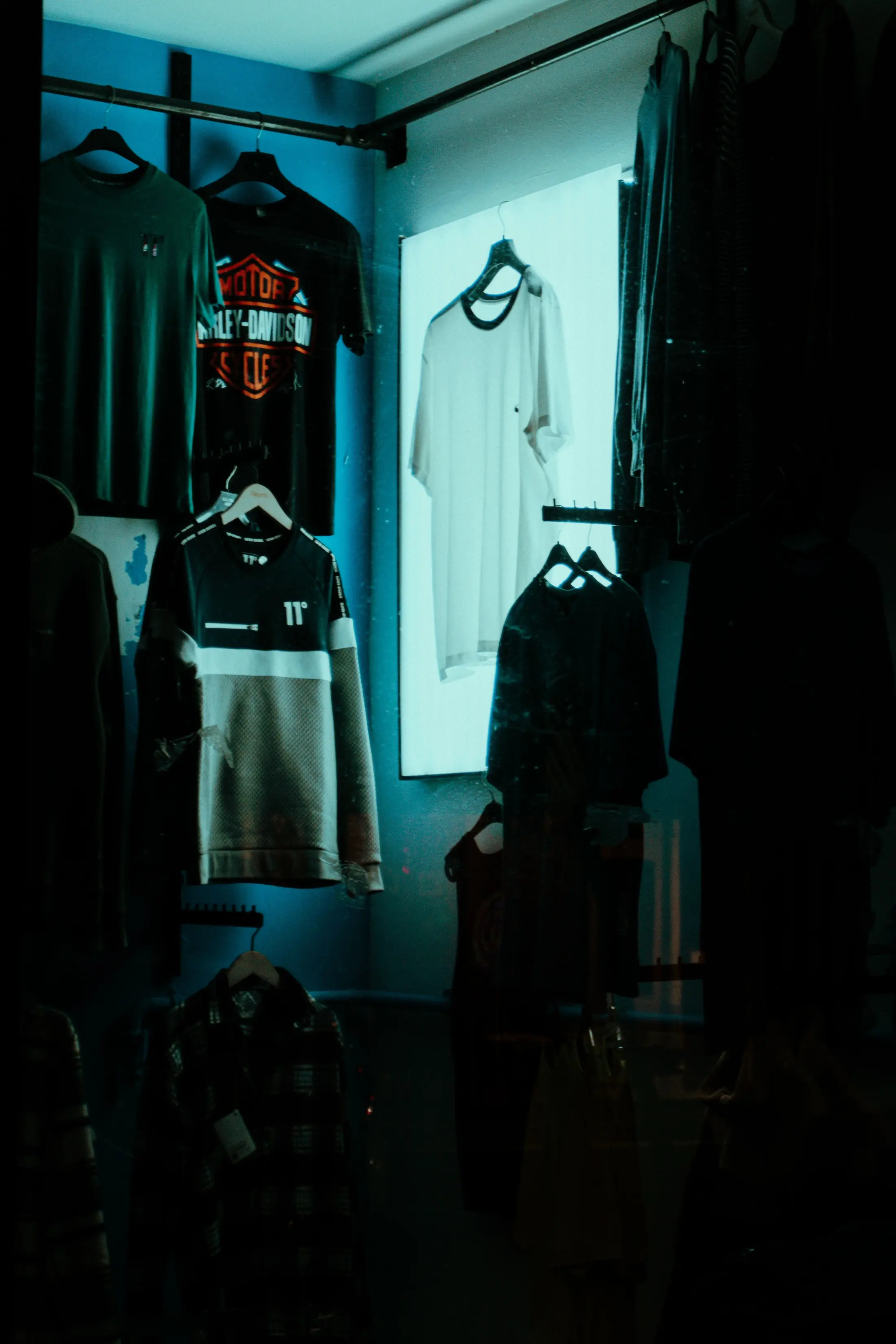 A walk-in closet with shirts hanging on a rack under ambient lighting